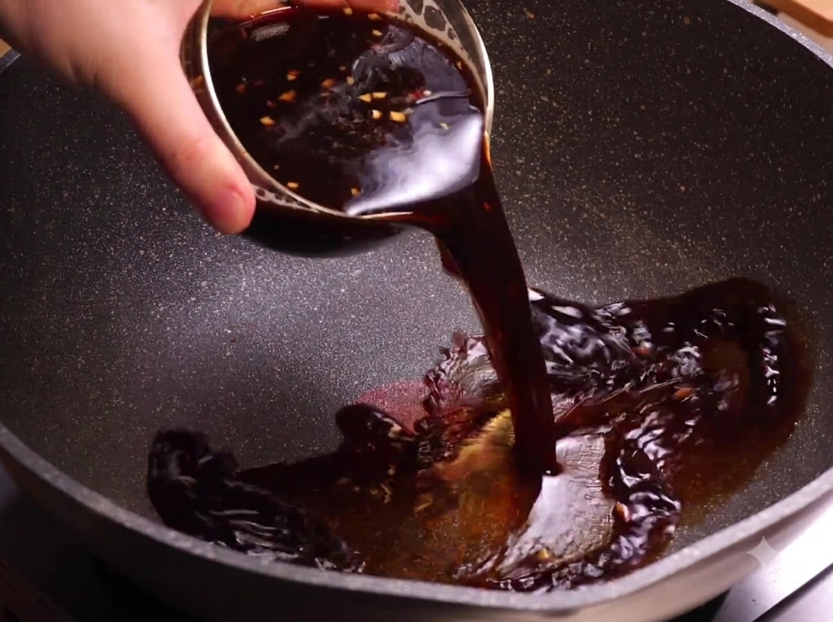 Una ciotola di salsa scura al caffè che viene versata in un wok riscaldato.