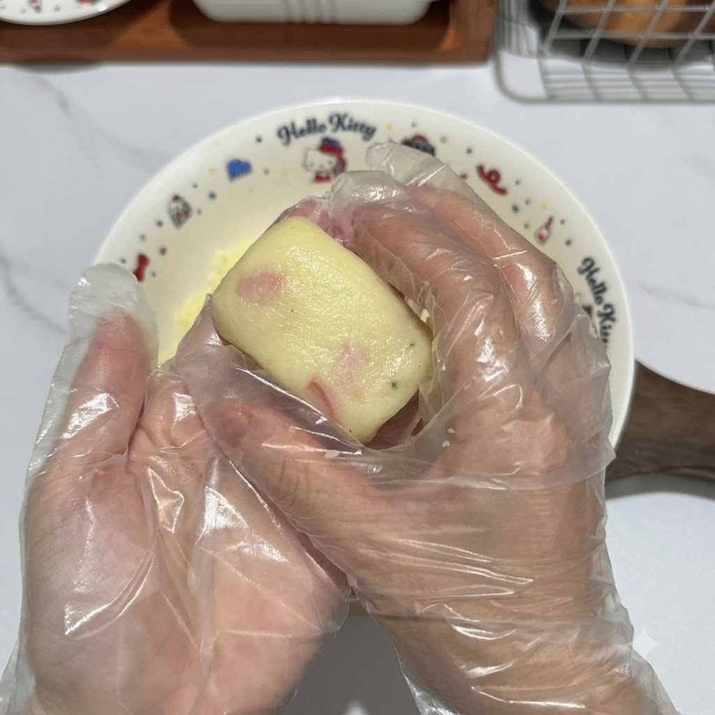 Mani con guanti che modellano un pezzo di impasto di patate in una crocchetta rettangolare pulita.