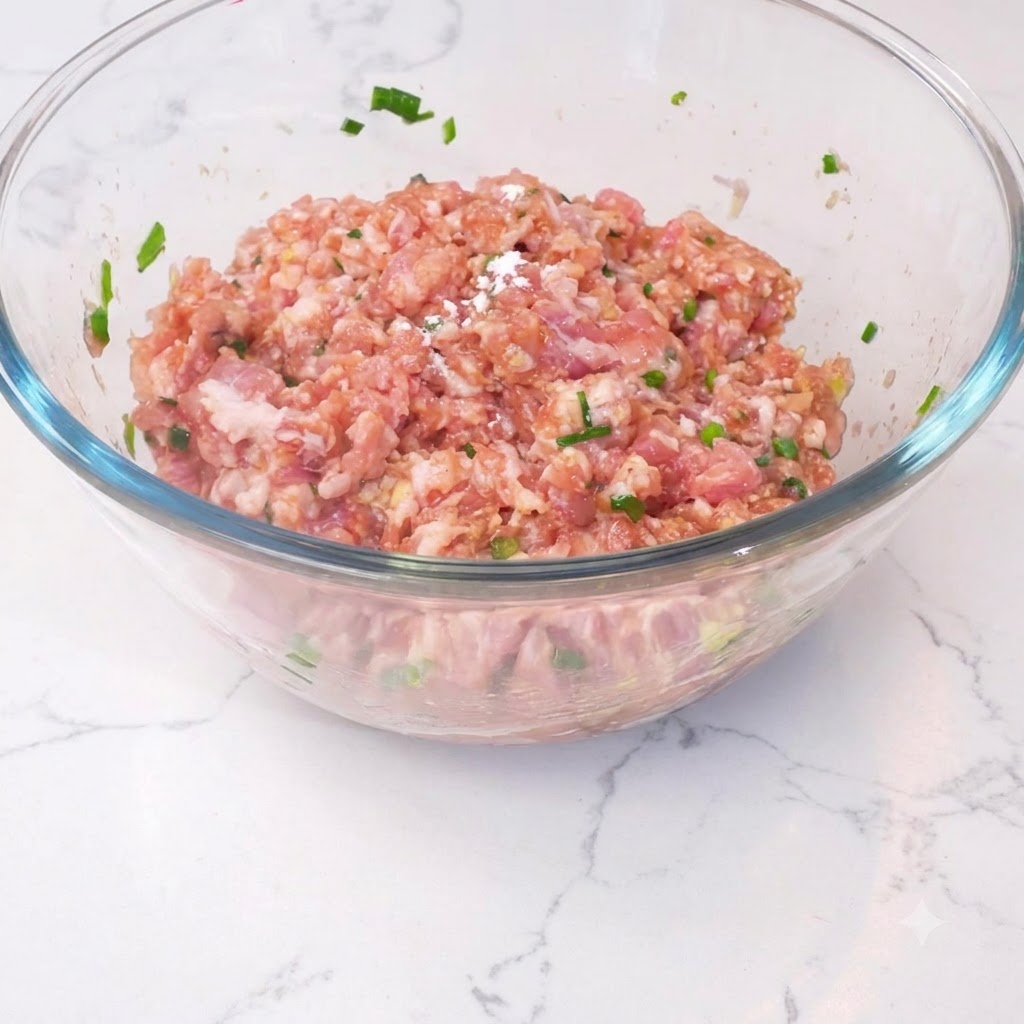 Amido di mais cosparso sul composto di carne in una ciotola di vetro.