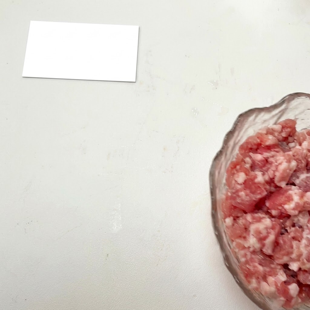 Carne macinata in una ciotola di vetro con i condimenti aggiunti.