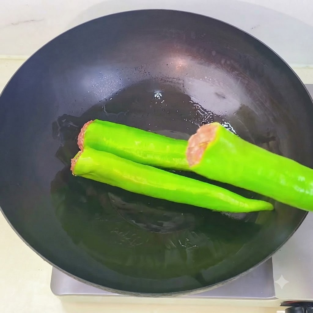 Peperoni verdi ripieni disposti in sequenza allinterno di un wok riscaldato con olio.