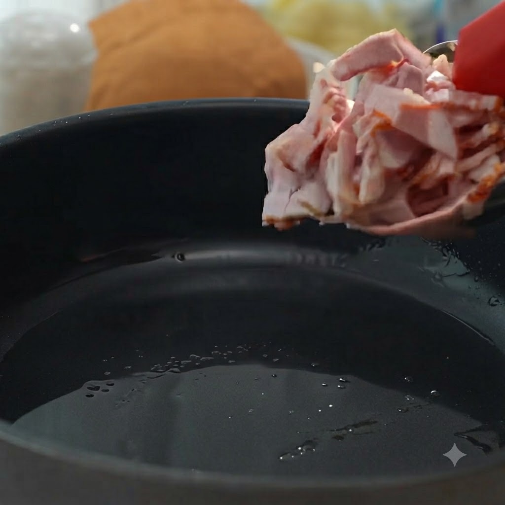 Pezzi di pancetta aggiunti in padella per essere fritti fino a doratura e croccantezza.