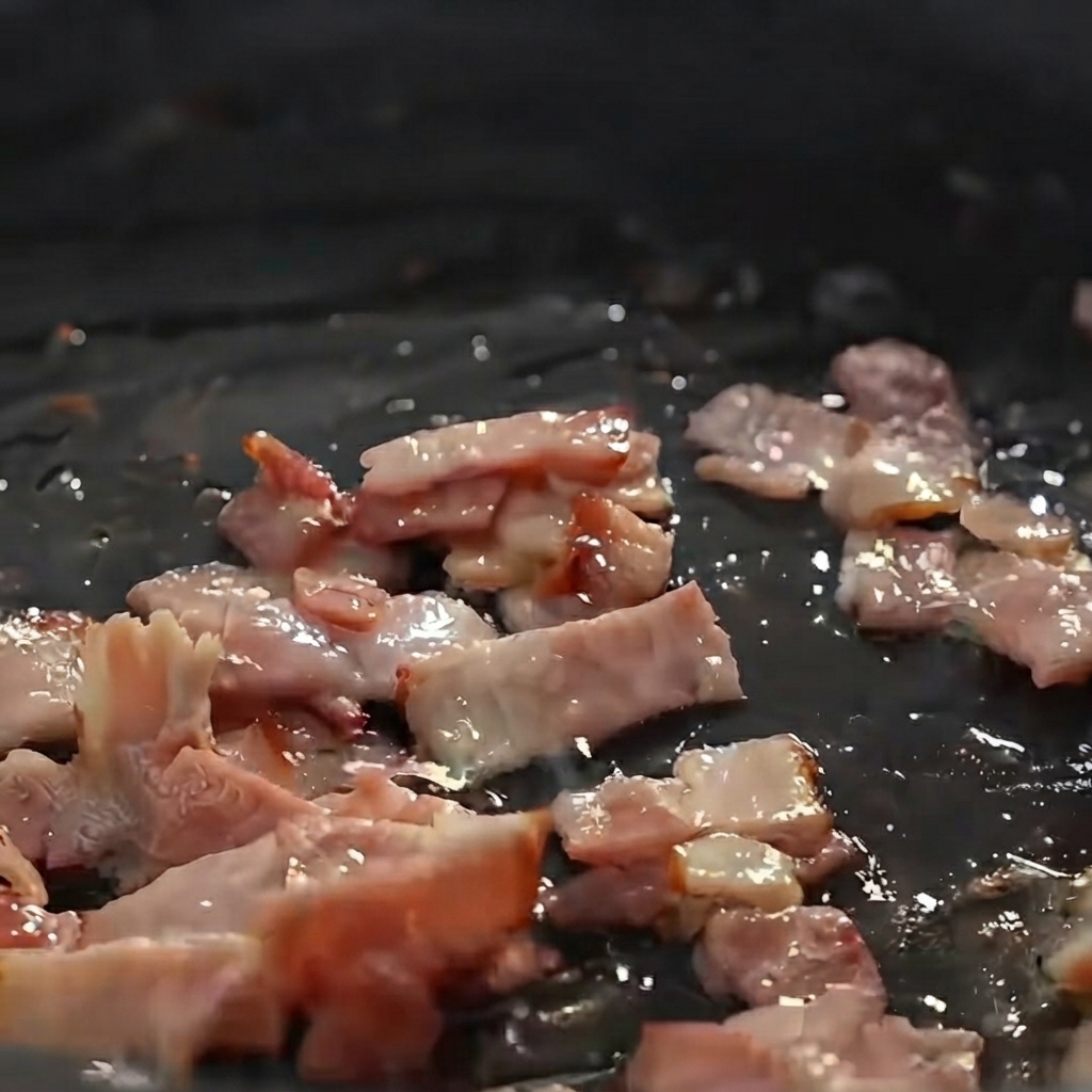 Patate, cipolle e sedano a dadini saltati con pezzi di pancetta in padella.