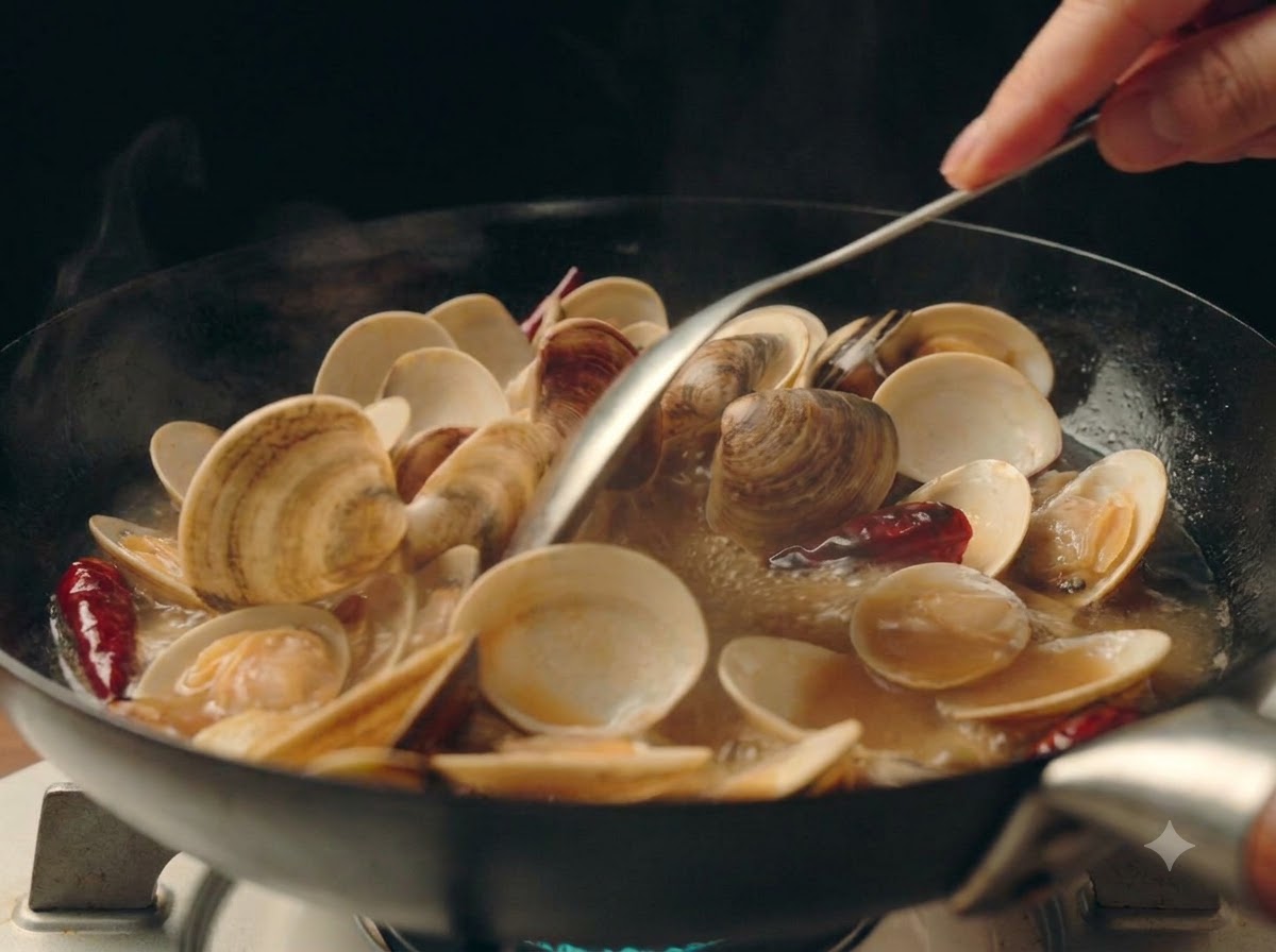 Cipollotti tritati finemente sparsi sopra le vongole ribollenti nella padella.