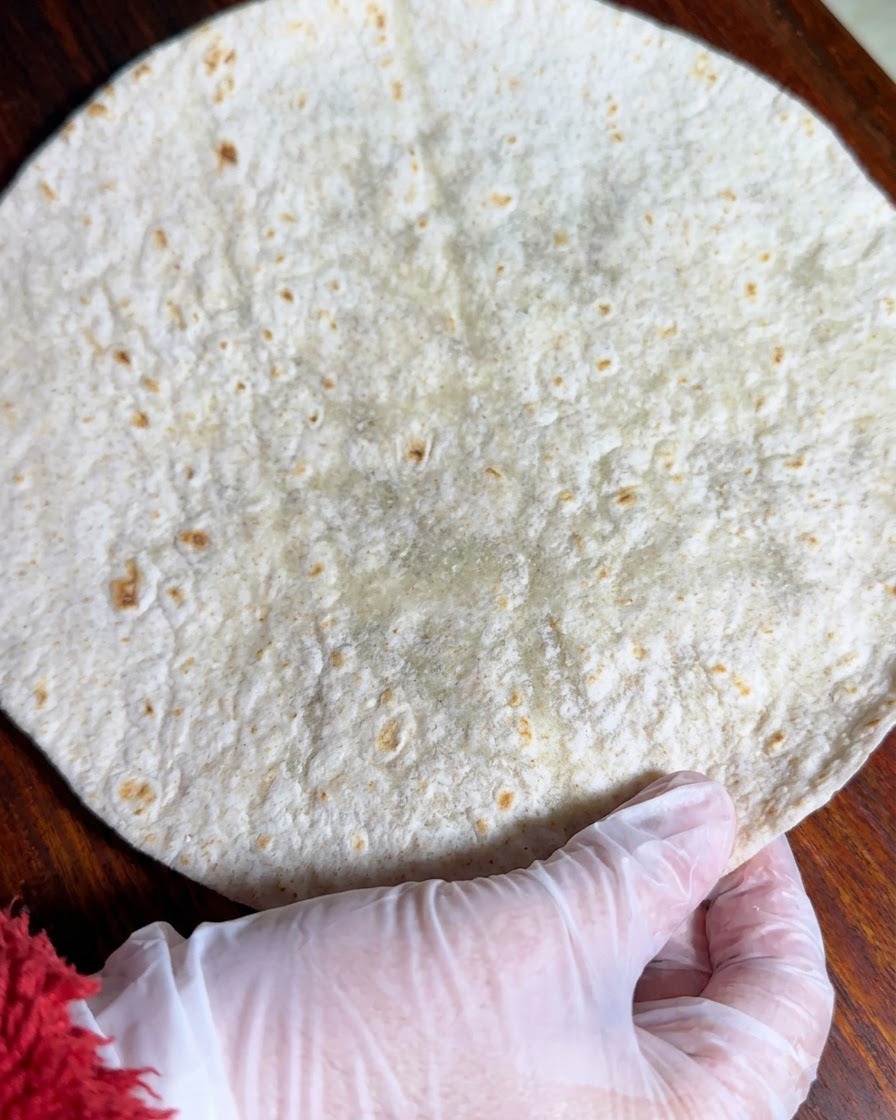 Una tortilla integrale stesa in piano su una superficie di legno.