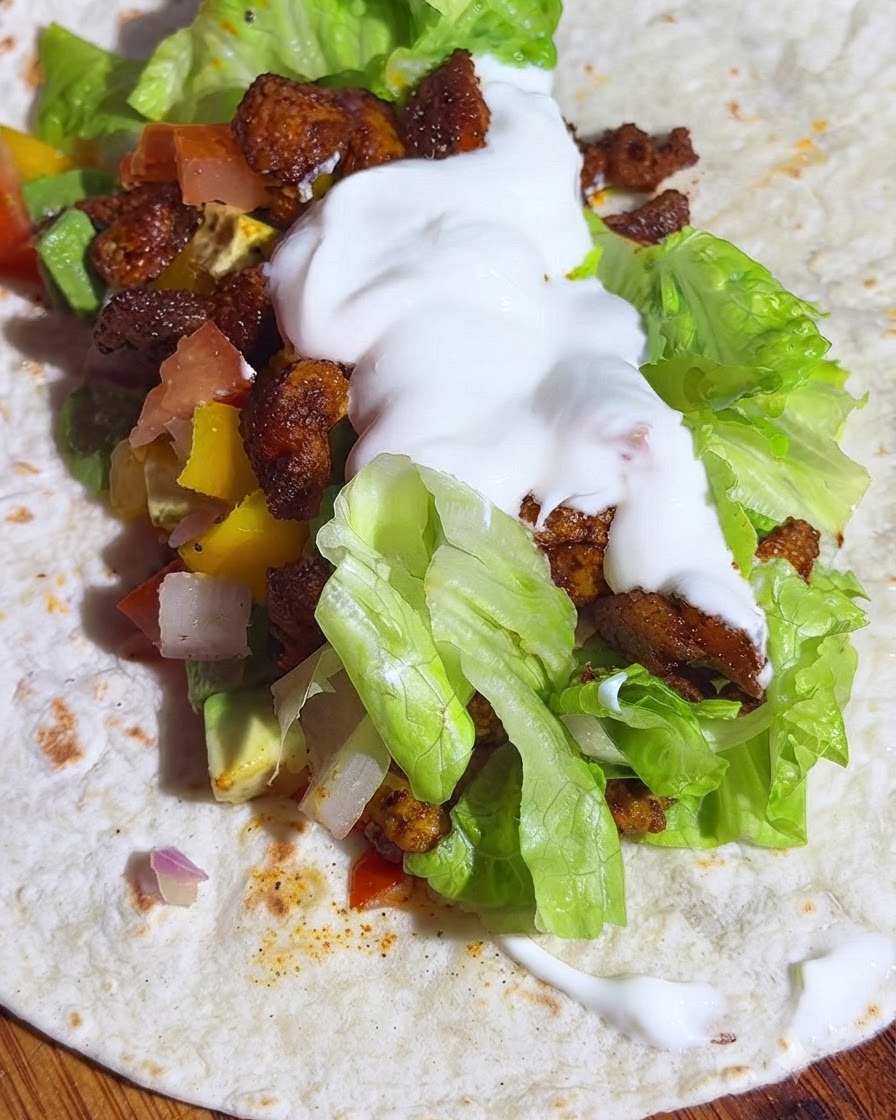 Una tortilla integrale farcita con lattuga, salsa di avocado, pollo e un cucchiaio di yogurt.