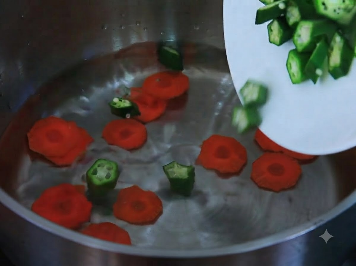 Carote affettate e okra tagliata che scivolano da un piatto bianco in una pentola piena dacqua.
