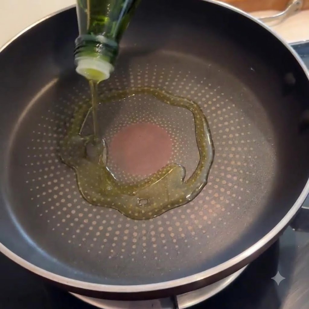 Pancetta sfrigolante in padella con un filo dolio doliva sul fondo.