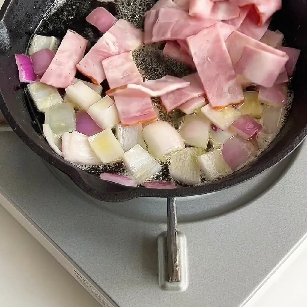 Pezzi di pancetta mescolati e saltati con le cipolle nella padella.
