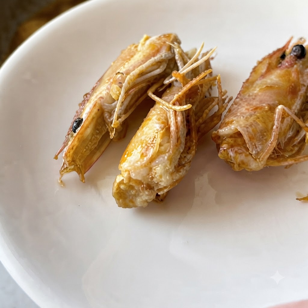 Aglio tritato finemente e peperoncino rosso che soffriggono nellolio brillante dentro una padella in acciaio inossidabile.