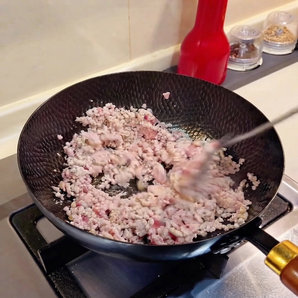 Cipollotti tritati e aglio tritato mescolati insieme alla carne macinata in un wok.