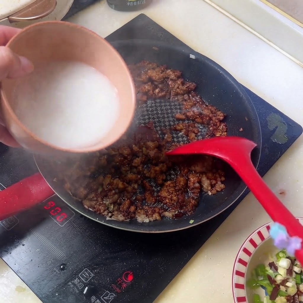 Acqua di fecola bianca versata da una ciotola nella padella della salsa di carne macinata scura.