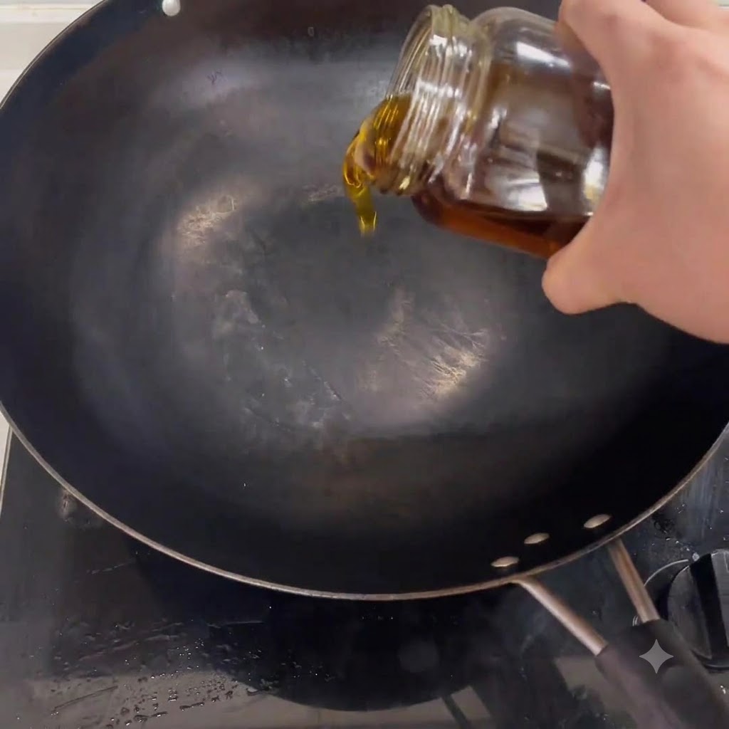 Olio da cucina che cola da un barattolo in un wok nero posizionato su un fornello.