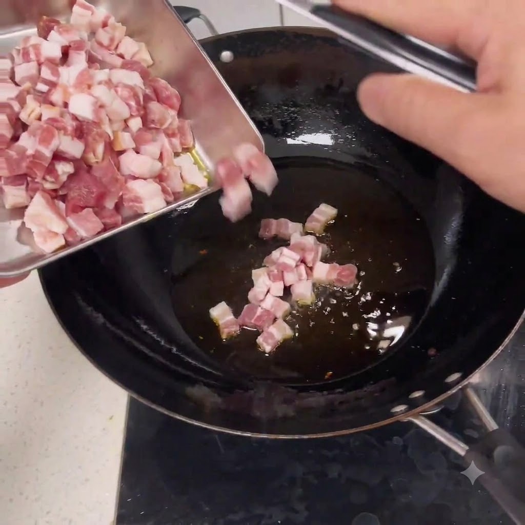Pezzi di maiale a dadini crudi che scivolano da un vassoio di metallo in un wok con olio caldo.