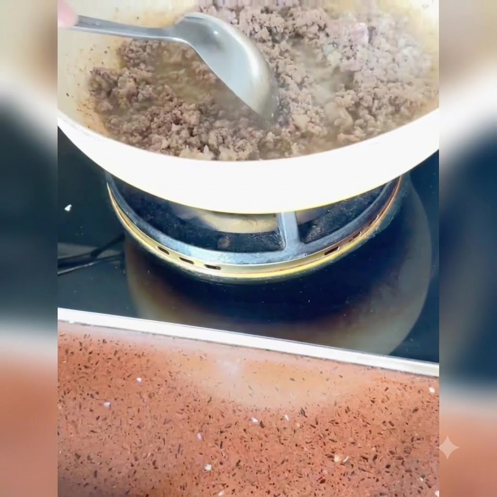 Cipollotti, zenzero e aglio tritati mescolati alla carne cotta nella padella.