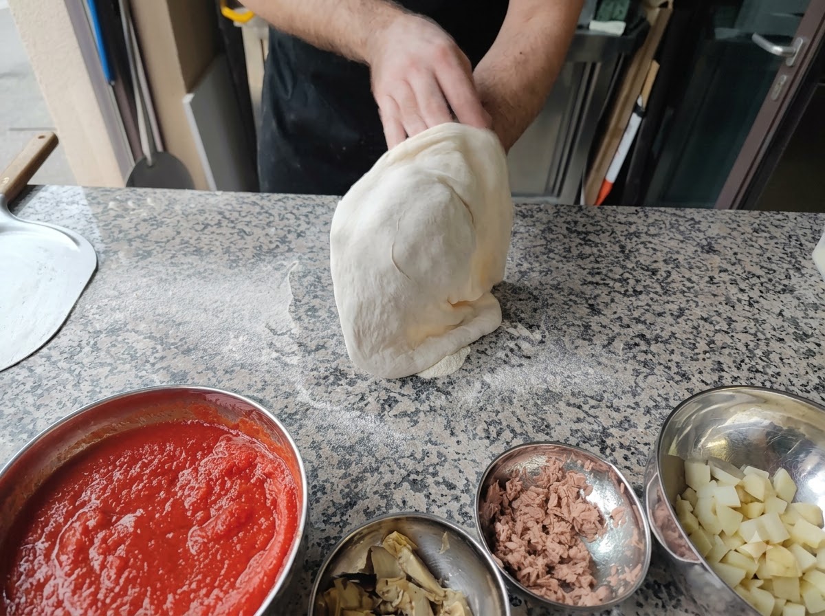 Una persona che allunga limpasto della pizza sui pugni in aria.