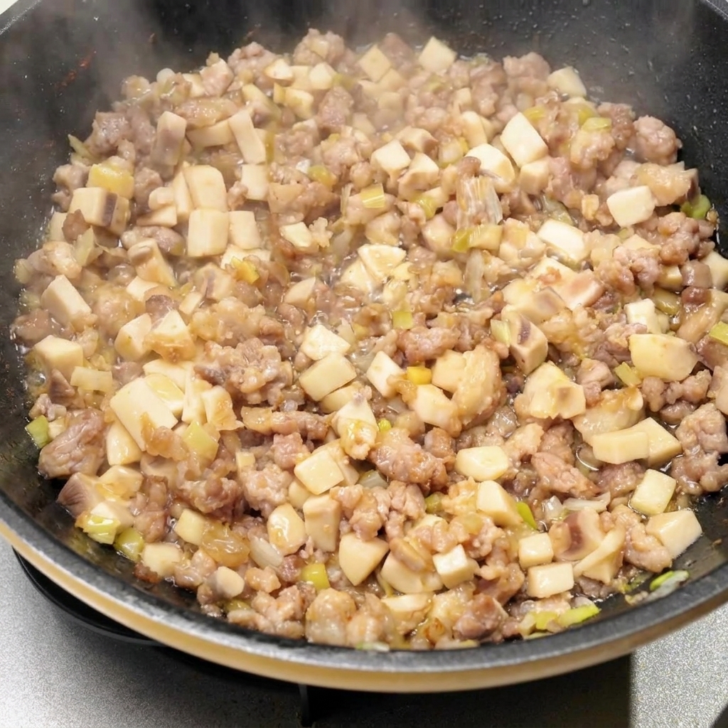 Vari condimenti liquidi e salse versati nella padella con il composto di carne e funghi.