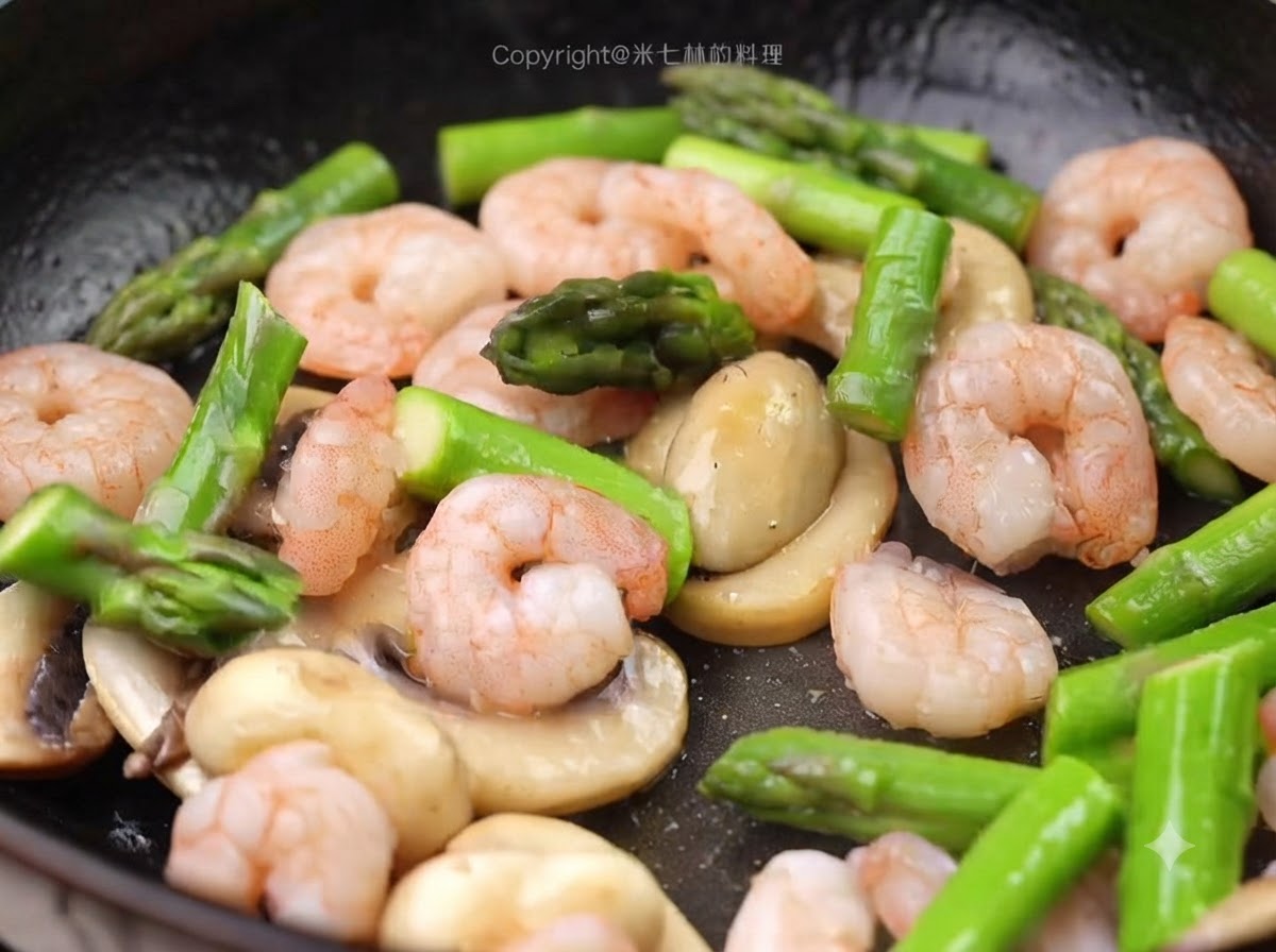 Gamberi sbollentati e pezzi di asparagi verdi aggiunti nella padella insieme ai funghi.