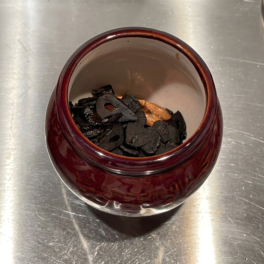 Olio aromatizzato allaglio versato dallalto in un mortaio di ceramica pieno di chips daglio fritte.