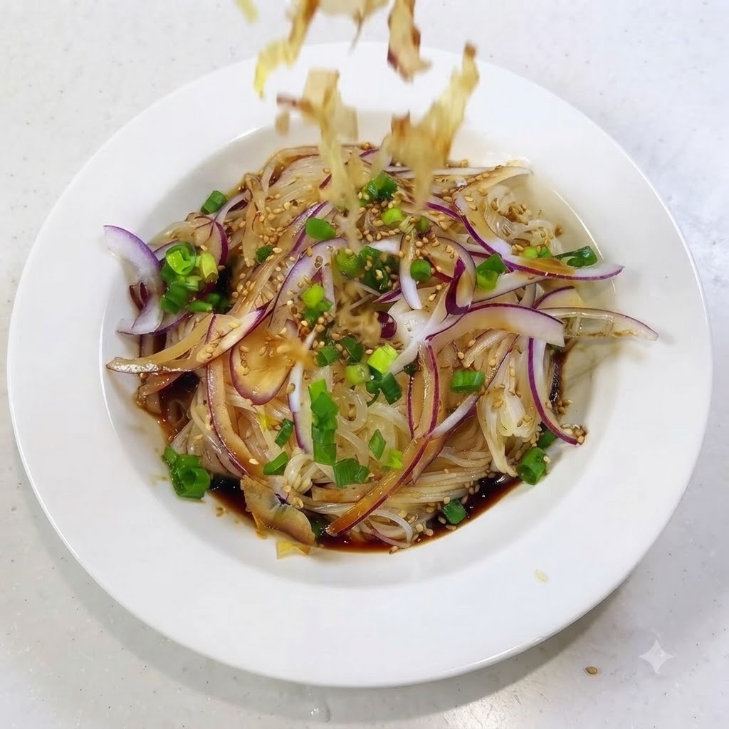 Scaglie di bonito che cadono e si spargono sopra il piatto di noodles preparato.