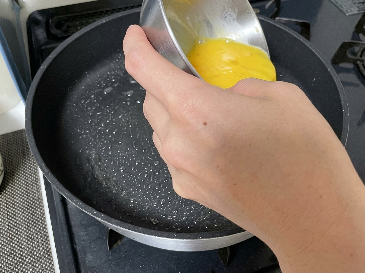 Liquido di uovo sbattuto versato in una padella unta.