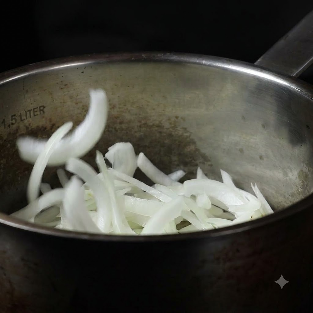 Cipolle affettate che vengono fatte cadere in una pentola da cucina in acciaio inossidabile.