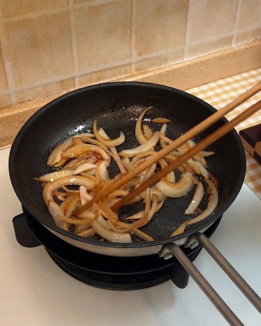 Strisce di cipolla saltate in padella con le bacchette di legno.