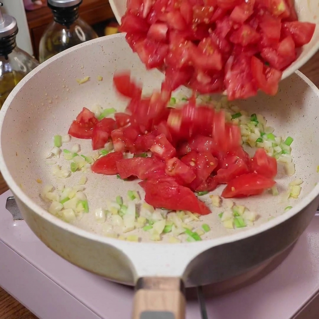 Pomodori a dadini versati in una padella con aromi soffritti.