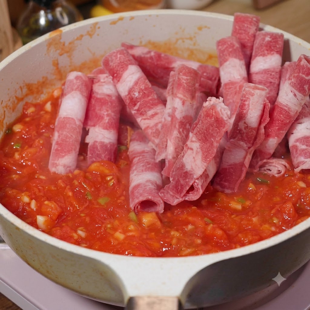 Manzo grasso affettato aggiunto in una padella con pomodori e saltato.