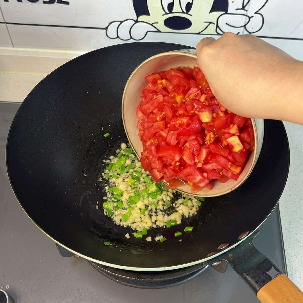 Pomodori rossi freschi tagliati a pezzi versati da una ciotola nel wok.