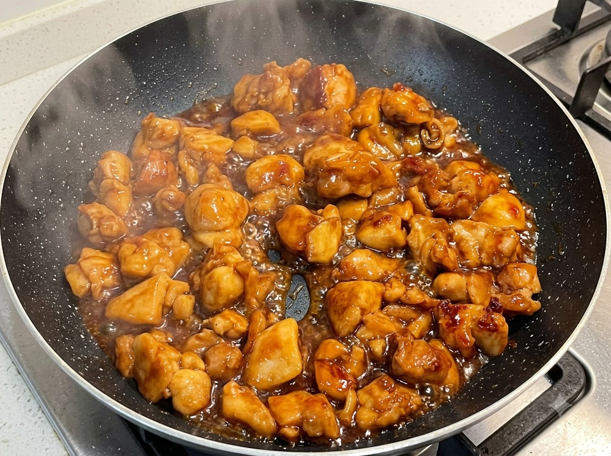 Pollo che cuoce a fuoco lento in una salsa densa allinterno di una padella.