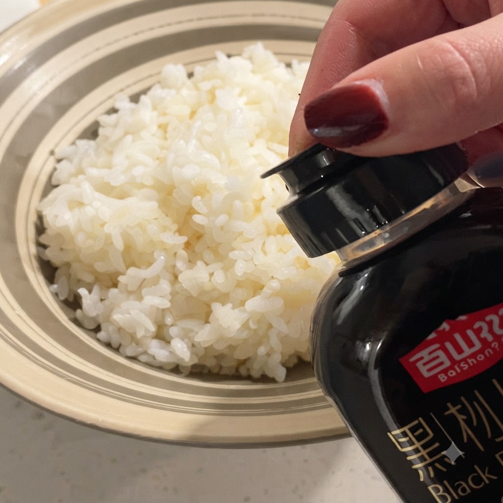 Salsa di tartufo nero fatta scendere da una bottiglia su una ciotola di soffice riso bianco al vapore.