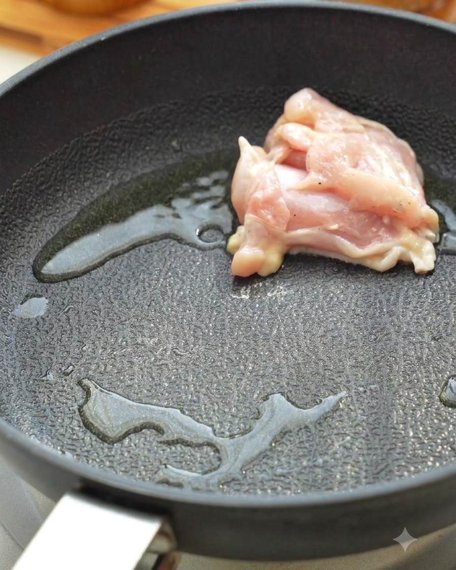 Pezzi di coscia di pollo crudi che rosolano in una padella calda con olio.