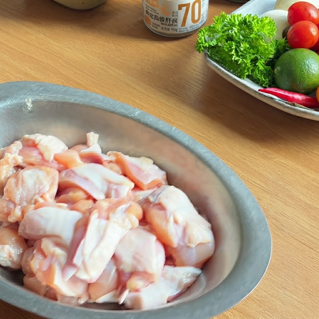 Una ciotola di metallo riempita con pezzi di pollo crudo conditi con salsa di soia scura, salsa di ostriche e pepe nero.