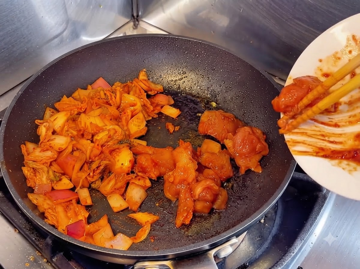 Utilizzo di bacchette per far scivolare pezzi di pollo crudo marinato da un piatto bianco in una padella accanto a kimchi e cipolle saltate.