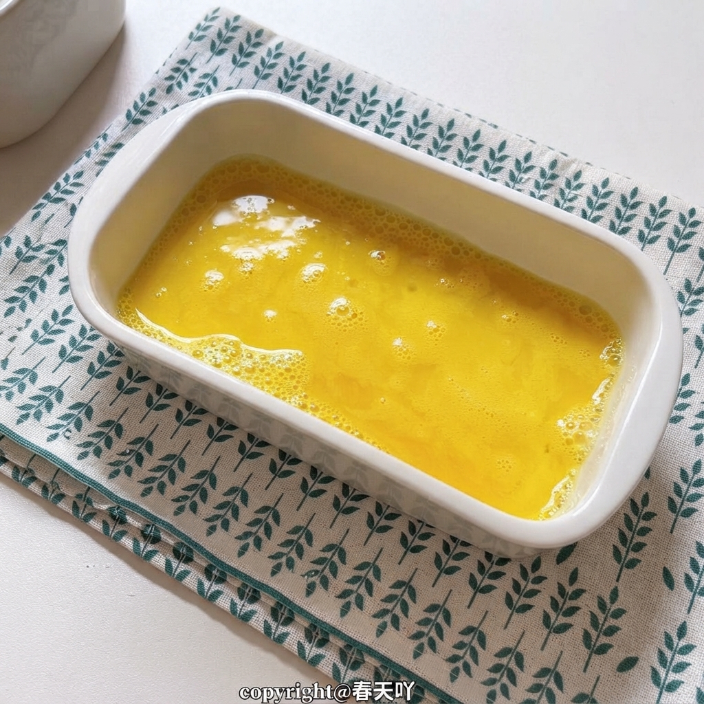 Un piatto di ceramica bianca pieno di uova sbattute giallo oro.