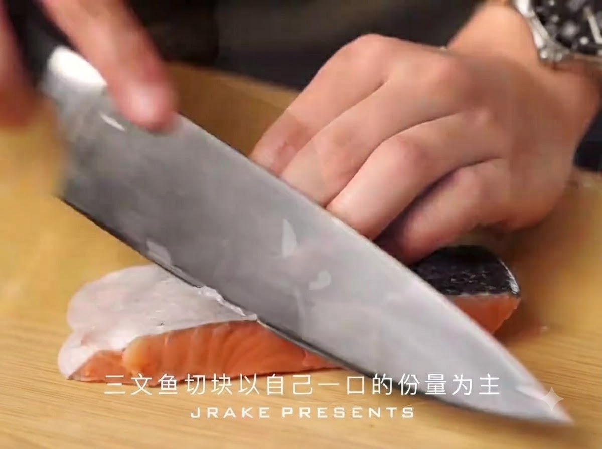 Un coltello da chef affilato taglia un filetto di salmone con la pelle a bocconcini su un tagliere di legno.