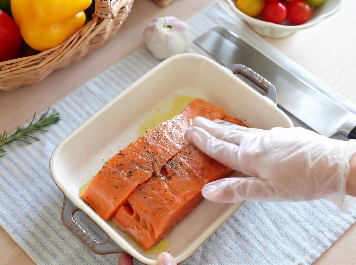 Una cipolla rossa tagliata finemente a piccoli pezzi su un tagliere di legno con un coltello affilato.