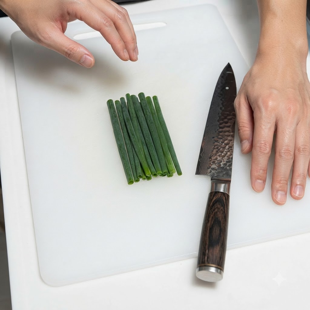 Un mazzetto di cipollotti ordinatamente disposti accanto a un coltello da cucina su un tagliere bianco.