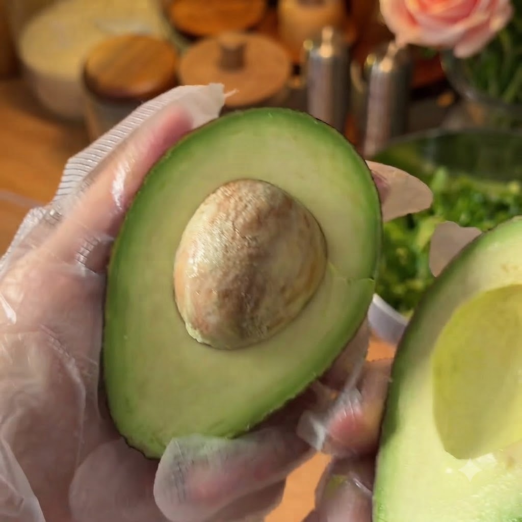 Un avocado fresco tagliato a metà preparato su un tagliere.