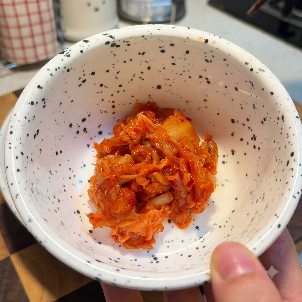 Una ciotola bianca maculata riempita con una porzione di kimchi tritato rosso vivo.