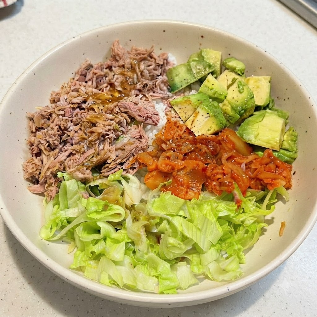 Una bowl di riso tonno e avocado assemblata con il condimento gocciolato sopra gli ingredienti.