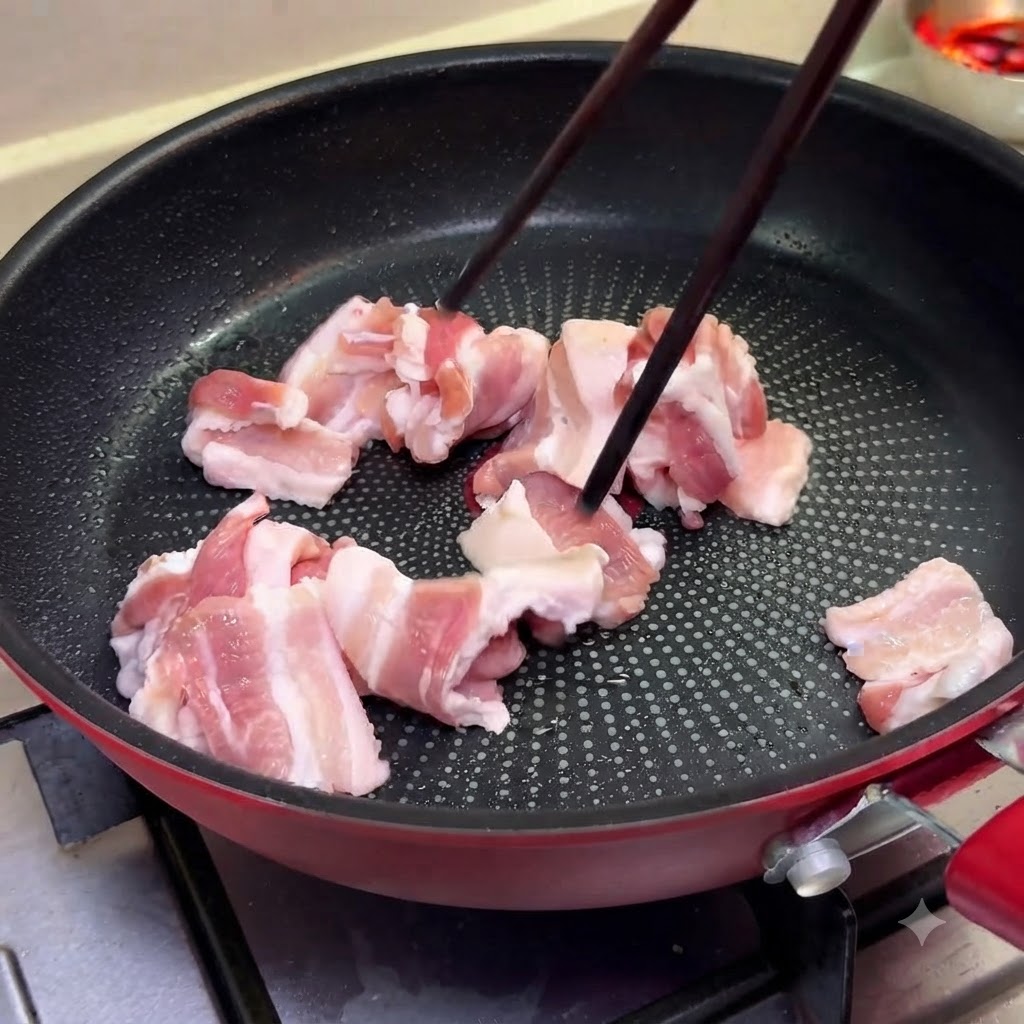 Fette sottili di pancetta di maiale che cuociono in una padella a fuoco medio usando delle bacchette.