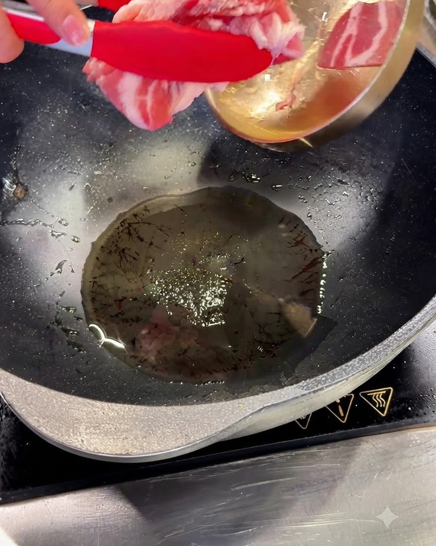 Fette di pancetta di maiale aggiunte allolio caldo in un wok usando pinze rosse.