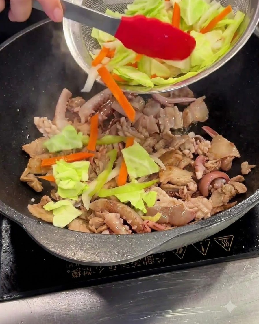 Cavolo e carote affettate aggiunte da un colino a maglie nel wok.