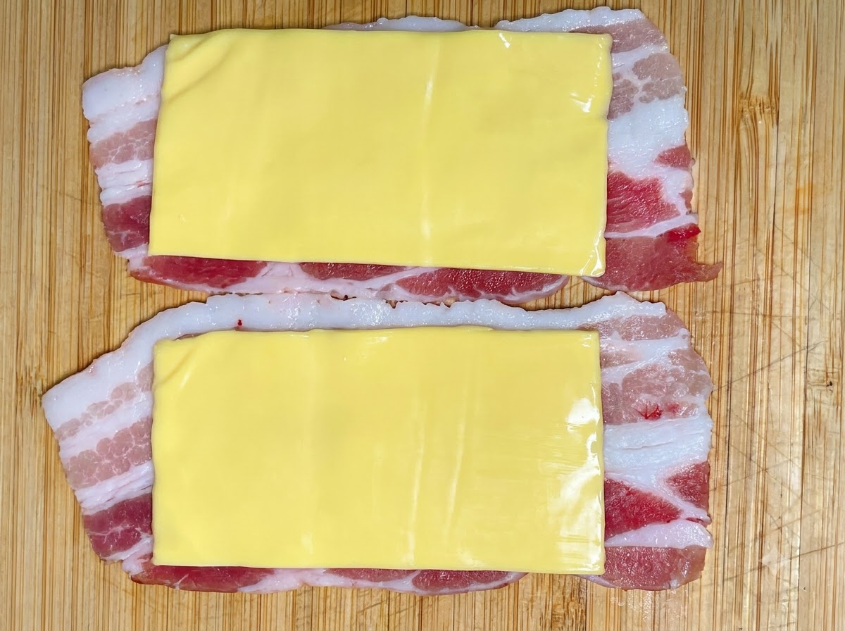 Una porzione di pasta di gamberi spremuta da una sacca da pasticcere sugli strati di formaggio e maiale.