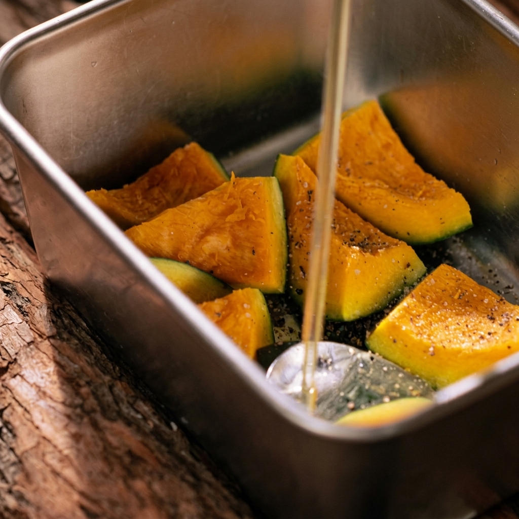 Spicchi di zucca mescolati con olio doliva e spezie allinterno di una teglia in metallo.
