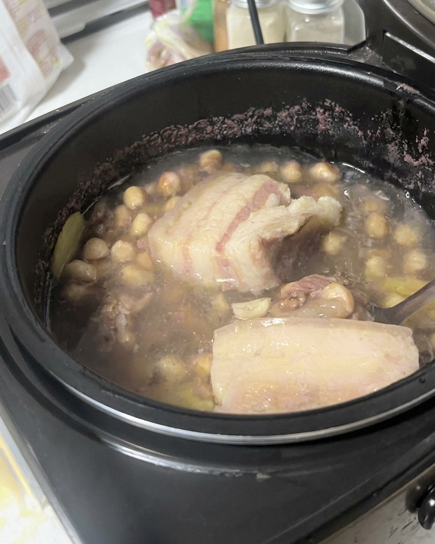 Pancia di maiale sollevata ed esaminata con un cucchiaio allinterno del composto di brodo.