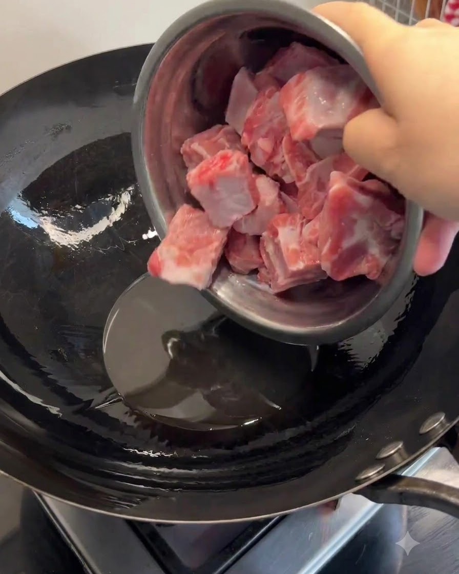 Costine di maiale aggiunte allo strutto sciolto in un wok riscaldato e saltate fino a doratura.