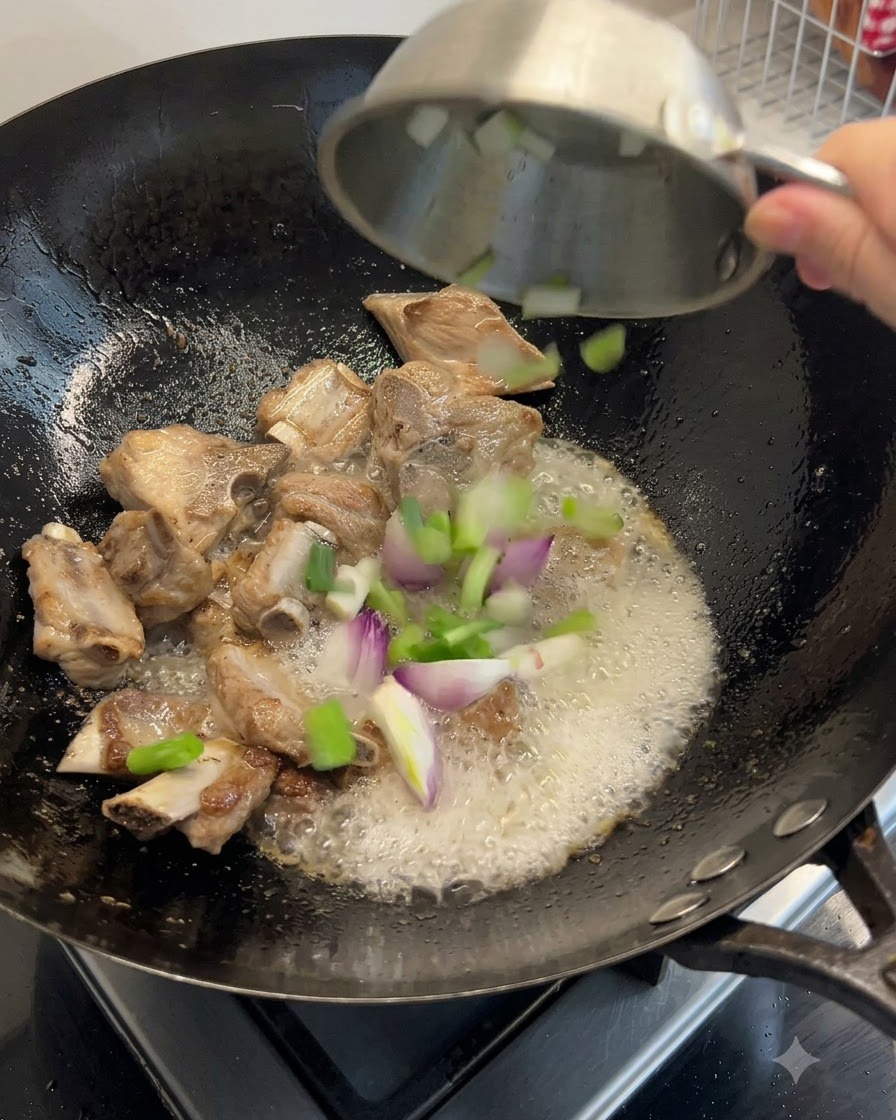 Cipollotti, zenzero e ingredienti di mare essiccati gettati nel wok insieme alle costine.